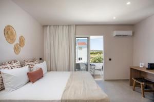 a bedroom with a large bed with a desk and a balcony at Pado Living in Faliraki