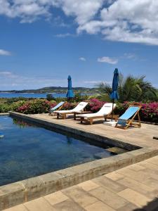 a swimming pool with lounge chairs and umbrellas at Résidences-Bel-R in Nosy Be