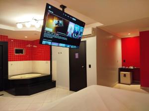 a bathroom with a tub and a tv hanging from the ceiling at iLi Motel in Aparecida de Goiânia