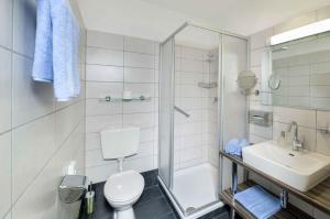 a bathroom with a toilet and a sink and a shower at Hotel Garni Sohler in Villach +15 photos