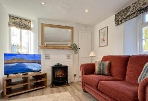 a living room with a red couch and a fireplace at Meads Cottage in Charmouth