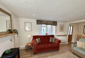 a living room with a red chair and a couch at Meads Cottage in Charmouth