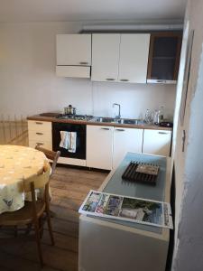 a kitchen with white cabinets and a table with a magazine at Casa vacanze Feltre in Feltre