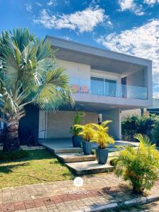 a house with palm trees in front of it at Rosa Internacional - Surfland in Praia do Rosa