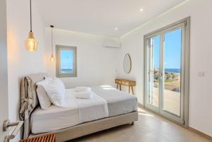 a white bedroom with a bed and a sliding glass door at Lipsi Grand Villas in Leipsoi