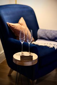 two wine glasses on a table next to a blue chair at The Coastal Haven, Broughty Ferry in Dundee