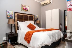 a bedroom with a large bed with an orange blanket at Little Haven! in Rustenburg +15 photos