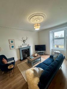 a living room with a blue couch and a fireplace at The Coastal Haven, Broughty Ferry in Dundee