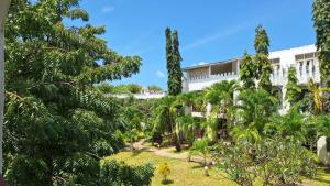 a garden in front of a building with trees at Malindi Sunset Apartments in Malindi