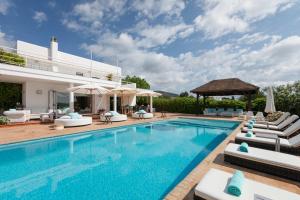 a swimming pool with chairs and a villa at Villa Mara- Close Playa den Bossa beach in Sant Jordi