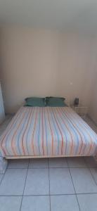 a large bed with a striped blanket on a floor at Les Eucalyptus in Vesseaux