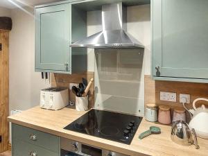 a kitchen with green cabinets and a stove top oven at 13 Doomgate Cottage - Uk45056 in Appleby
