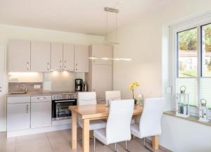 a kitchen with a wooden table and white chairs at Haus Hanse in Korswandt