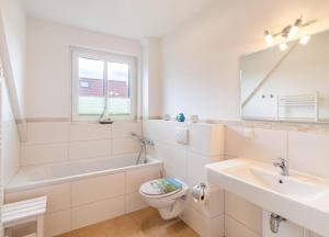 a white bathroom with a tub and a toilet and a sink at Haus Hanse in Korswandt +8 photos