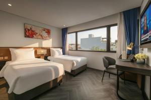 a hotel room with two beds and a desk at Sora Hotel Hanoi in Hanoi
