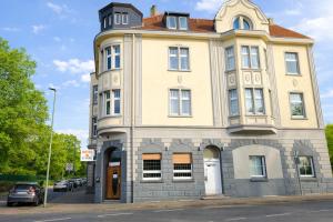 a yellow building with a clock tower on a street at Sonne Hotel in Herne