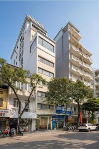 a tall white building with trees in front of it at Sora Hotel Hanoi in Hanoi