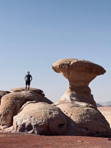 a man standing on top of two large rocks at Local experience in El Quweira +7 photos