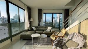 a living room with a couch and chairs and windows at Sunrise Gurney Georgetwon in George Town