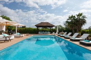 a swimming pool with chairs and a gazebo at Villa Mara- Close Playa den Bossa beach in Sant Jordi