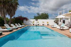 a swimming pool with lounge chairs and an umbrella at Villa Mara- Close Playa den Bossa beach in Sant Jordi