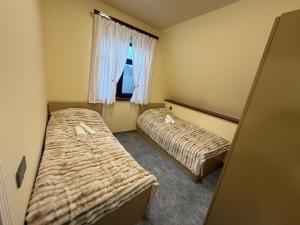 two beds in a small room with a window at Boss House in Quba