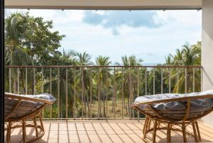 a balcony with two chairs and a view of palm trees at Ocean Villa in Ko Phangan