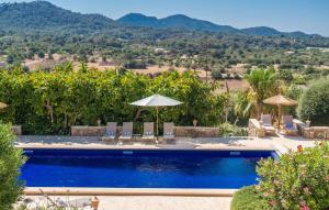 a pool with chairs and umbrellas and mountains in the background at Casa Amorena in Felanitx