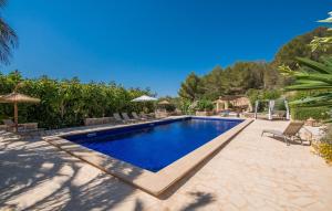 a pool with chairs and umbrellas in a backyard at Casa Amorena in Felanitx