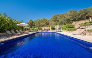 a blue swimming pool with chairs and an umbrella at Casa Amorena in Felanitx
