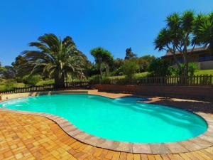 a swimming pool in a yard with palm trees at Into the Sunset Manor in Gordonʼs Bay