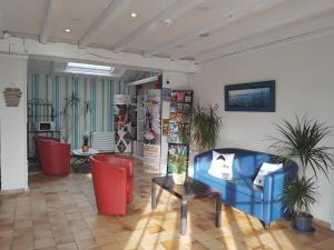 a lobby with a blue couch and two red chairs at Hotel La Chaumière in Saint-Jean-de-Monts