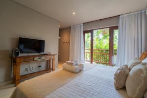a bedroom with a large bed with a tv and a window at D'amo Hotel Boutique in Trancoso
