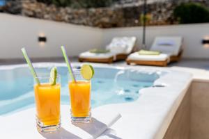 two glasses of orange juice next to a swimming pool at Seafront Holiday Home - Private Jacuzzi in Blato
