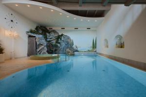 a large swimming pool in a building with a mountain at Dolomites Wellness Hotel Savoy in La Villa