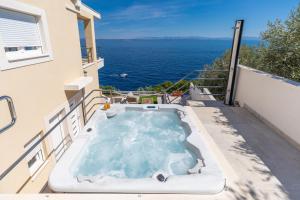 a hot tub on the balcony of a house with the ocean at Seafront Holiday Home - Private Jacuzzi in Blato