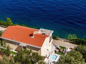 a house with a red roof next to the water at Seafront Holiday Home - Private Jacuzzi in Blato