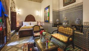 ein Schlafzimmer mit einem Bett, einem Tisch und Stühlen in der Unterkunft Riad Fes Maya suite & spa in Fès