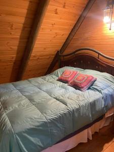 a bed with two pillows on it in a attic at Cabañas Rahue in Vilches
