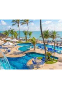 a resort with a swimming pool with palm trees and the ocean at RESORT PITANGUI BEACHs in Extremóz