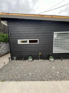a black garage with two potted plants in front of it at Cabañas Varas in Osorno
