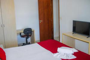 a room with a bed and a desk and a television at TerrazzoPontaNegraDJ in Natal
