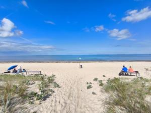 a group of people sitting on benches on the beach at FeWo Renken in Trassenheide