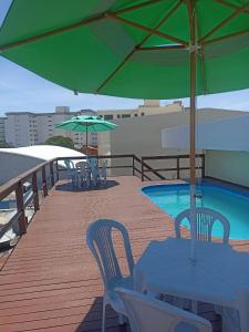 a deck with tables and chairs and an umbrella at Orla de Araruama in Araruama