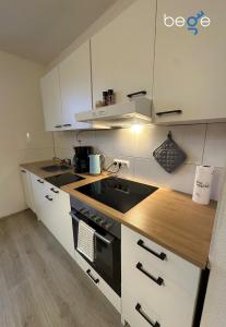 a kitchen with white cabinets and a stove top oven at BEGE APARTMENTS Next Level Sleep in Niederdorla