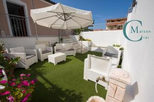 a patio with white chairs and an umbrella at Residenza Magnolia in Tropea