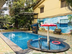 a swimming pool with a red umbrella next to it at Rajdhani Resort Lonavala in Lonavala +31 photos