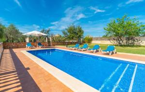 a swimming pool with blue chairs and an umbrella at Sa Vileta in Sencelles