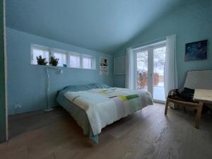 a blue bedroom with a bed and a window at Agerdal - dejligt hus midt i mark og have in Nykøbing Mors
