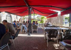 a group of people sitting at tables under a red umbrella at Logis Hôtels - Hôtel et Restaurant Le Lion d'Or in Gramat +22 photos